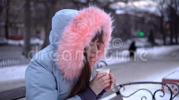 一个年轻的女人试图在寒冷的冬天用热饮料取暖。