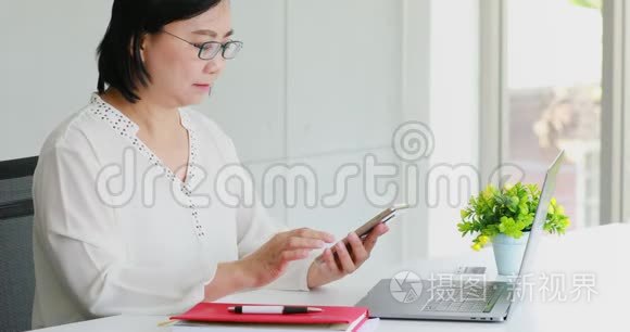 亚洲女商人在办公室里用手机。