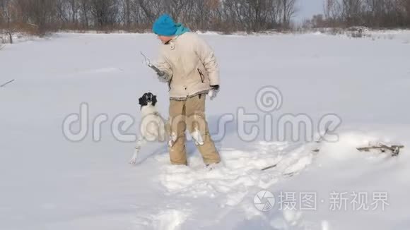 男孩少年在雪地里和狗玩得很开心。