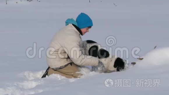 男孩少年在雪地里和狗玩得很开心。