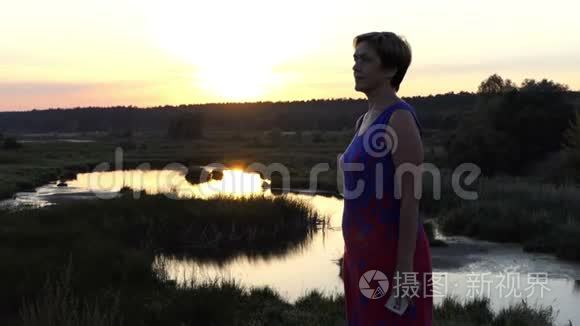 美丽的女人在日落时呼唤湖岸视频