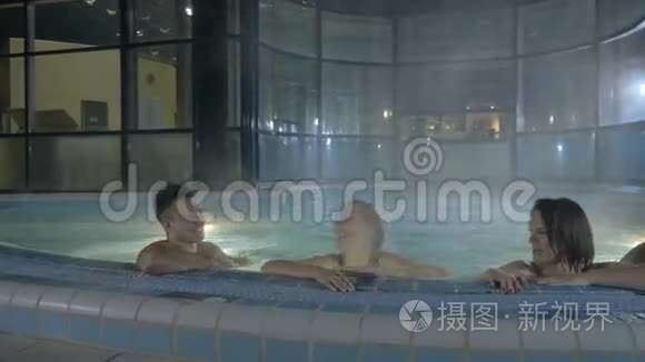 两个男人和两个女孩在桑拿后在游泳池里游泳