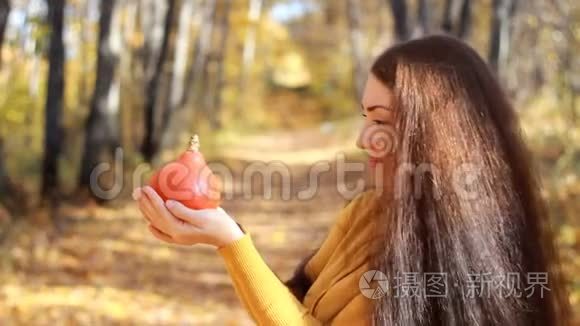 在森林里一个秋天的晴天，长发美女手捧南瓜