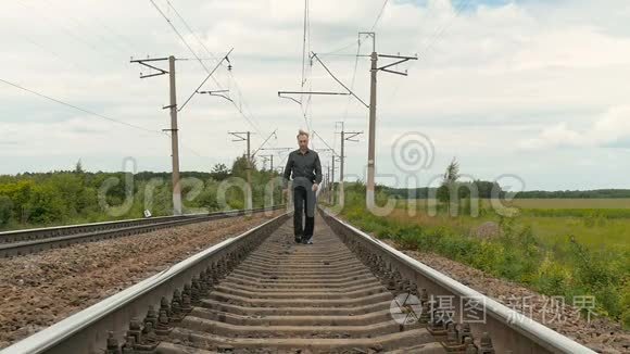 一个忧郁的人沿着铁轨走着视频