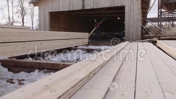 一个人在锯木厂的院子里堆着一堆装着木板的工作