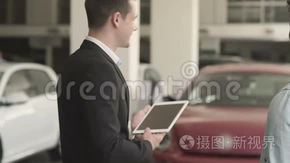 经理带着平板电脑在汽车陈列室向顾客展示汽车