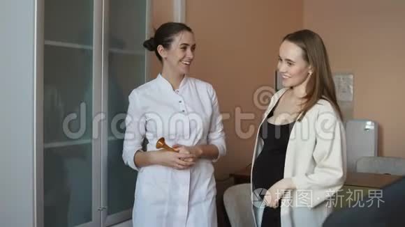 一位女医生和一位年轻的孕妇正站在办公室里谈论母性。
