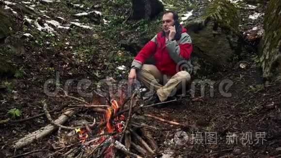 中年人坐在森林里的炉火旁视频