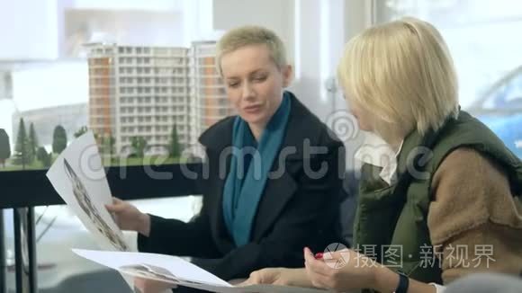 两个女人坐在笔记本电脑前的办公室里说话