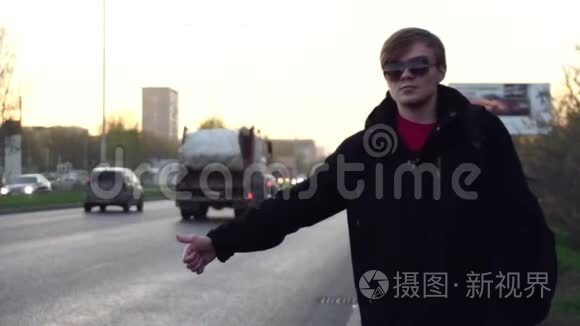 有魅力的人正在路附近乘出租车。 年轻的快乐男子在欧洲的街道上搭出租车。 高加索人的肖像