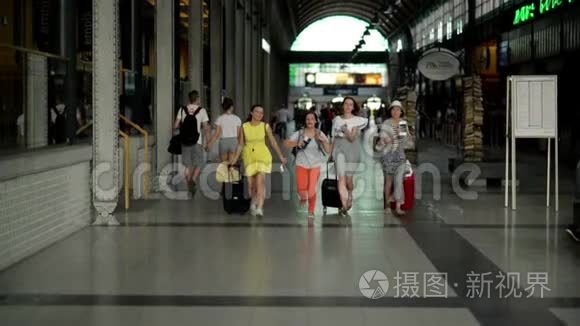 一群年轻女性在机场内奔跑，手里拿着文件、机票和大手提箱。 漂亮的女孩