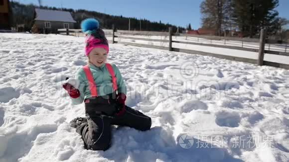 女孩正在镜头前扔雪球，享受外面温暖的冬天天气。 女性儿童在户外活动期间