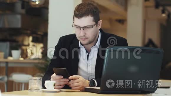 穿着商务服的人在咖啡馆里用笔记本电脑和手机工作
