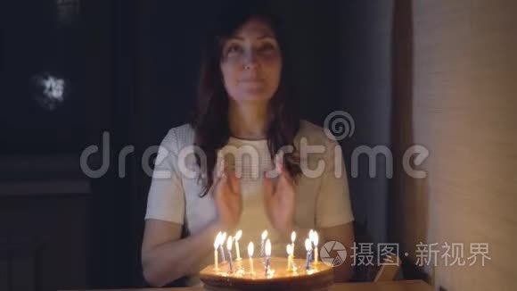 美丽的女人在节日蛋糕上吹蜡烛