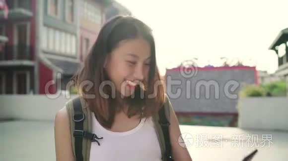 开朗美丽的年轻亚洲背包客博主女士在唐人街旅行时使用智能手机自拍。