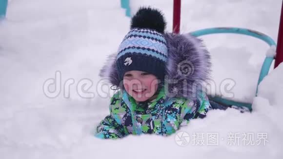 一个小孩在冬天的公园里玩雪.. 躺在白色蓬松的雪上微笑的婴儿。 新鲜的乐趣和游戏
