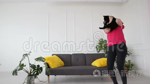 对宠物的爱。 漂亮的黑发女孩和一只黑猫在客厅的家里跳舞