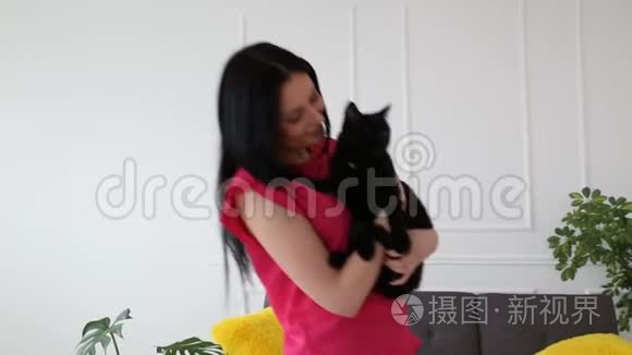 对宠物的爱。 漂亮的黑发女孩和一只黑猫在客厅的家里跳舞