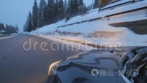 黑色的汽车与前灯在道路上移动沿雪覆盖的树木和山丘。