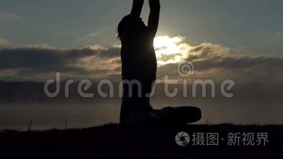灵性的人坐在湖岸上，在日落时缓慢地练习瑜伽