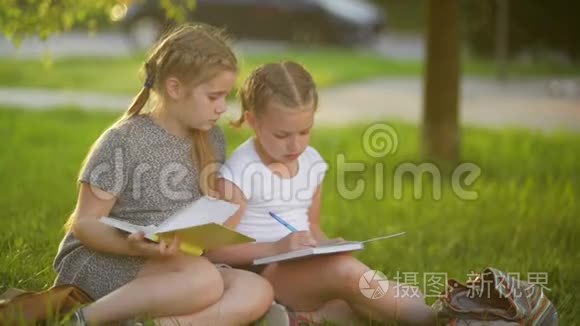 女孩在夏天的花园里做作业。 他们在获得知识方面玩得很开心。