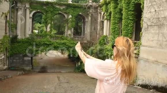 一个旅游的女孩为一座扭曲着常春藤的古老城堡的美丽拼贴画拍照。