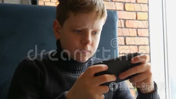 少年在黑色智能手机上玩游戏