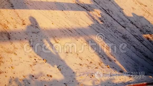 在沙滩上，一个人用一根沉重的绳子做运动的影子，交叉着。 日出时，夏天