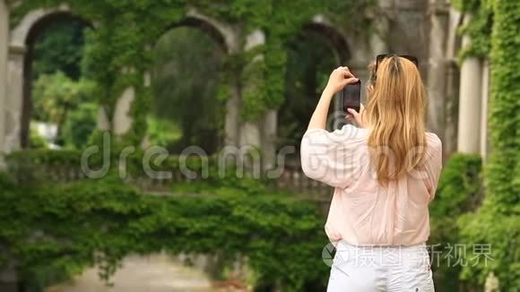 一个旅游`的女孩为一座扭曲着常春藤的古老城堡的美丽拼贴画拍照。