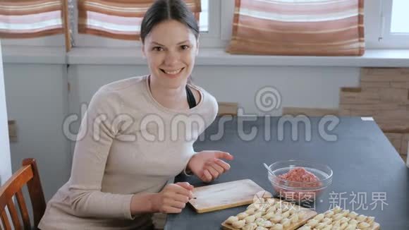 女人用肉馅包饺子，看着镜头微笑。