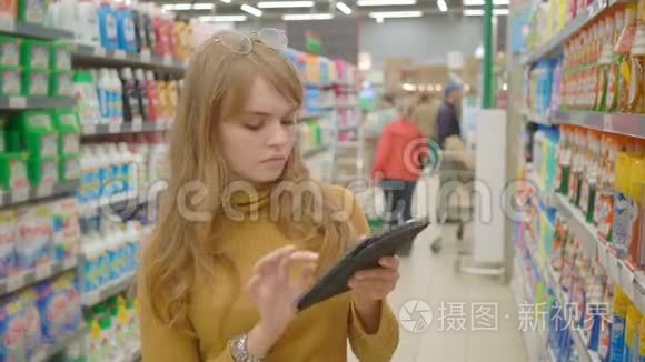 女性在超市购物，并在平板电脑技术和零售概念上使用移动应用程序