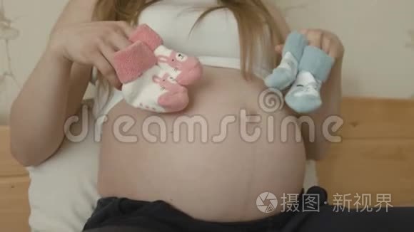 孕妇为新生儿穿着粉色和蓝色袜子