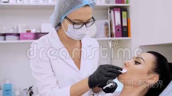 在诊所的美容室里，医生用无菌餐巾纸擦拭病人的嘴唇，然后注射透明质酸