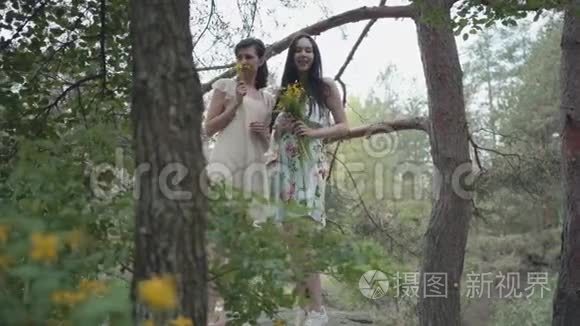 两个穿着短裙的美女站在岩石上，开着野花，看着森林