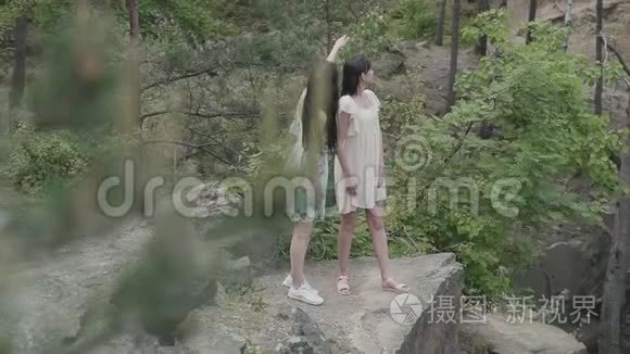 两个穿着短裙的美女站在岩石上，开着野花，看着森林