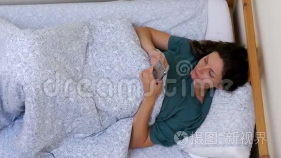 早上躺在一张白色床上的女人使用智能手机的俯视图