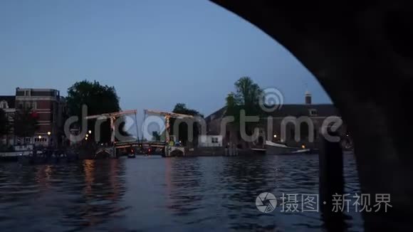 阿姆斯特丹的夜景。 由照明、建筑和路灯装饰的运河、经过桥下的船只。