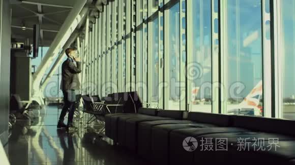 在机场，一个年轻而开朗的商人在用手机说话