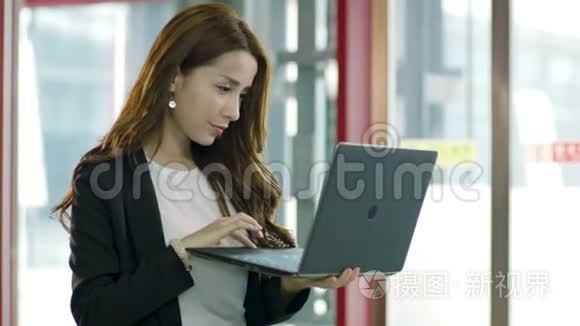 在电梯厅使用笔记本电脑的亚洲商界女性