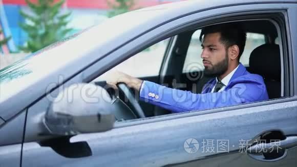 穿西装的人开车。 带着严肃面孔的穆斯林男子开着左撇子。