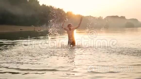 一个孩子在海里玩耍，产生了水的飞溅。 新鲜空气中的乐趣和游戏。 日落时间