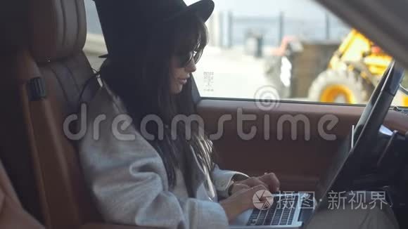 时尚女孩在车里用笔记本电脑视频