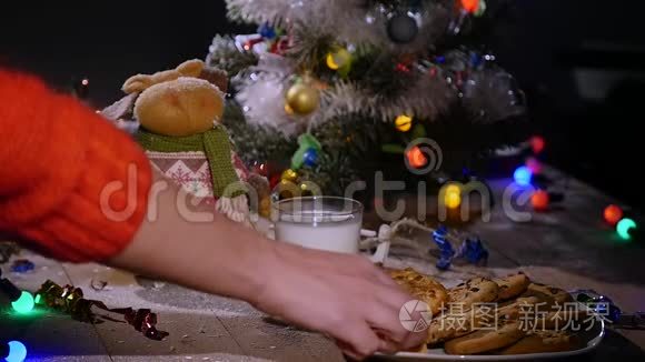 木制棕色桌子，上面装饰着圣诞用品和花环。 男人`手从盘子里拿饼干