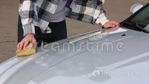 这个人用海绵仔细地清洗他最喜欢的汽车。洗车自助服务