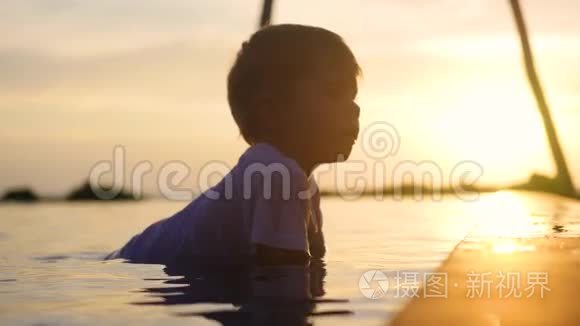 孩子坐在水里玩喷水.. 日落时间