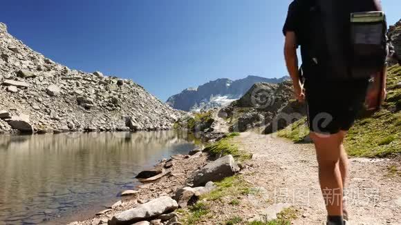 两人在田园诗般的山景中徒步旅行，有水晶湖高山峰和冰川。 夏日冒险