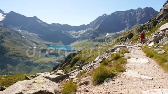 在蓝湖、高山峰和冰川的田园山景中，女子徒步旅行。 阿尔的夏日冒险