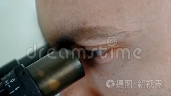 男性研究员通过显微镜观察视频