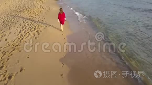 在潮湿的沙滩上赤脚行走的女人的后景。 海浪冲刷着沙滩上的脚印