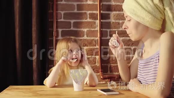 一个年轻的女人和一个小女孩在早餐时吃酸奶。